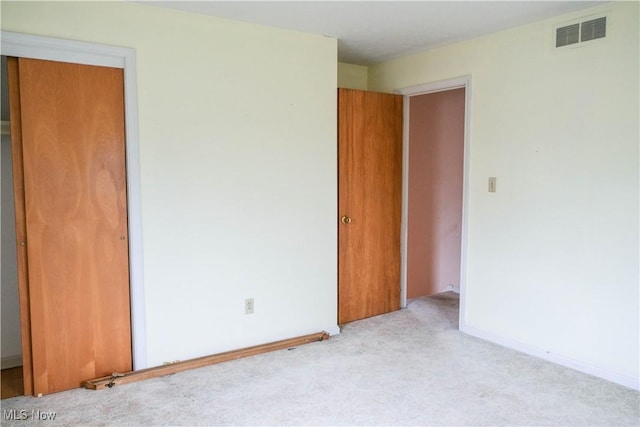 unfurnished bedroom with light carpet and a closet