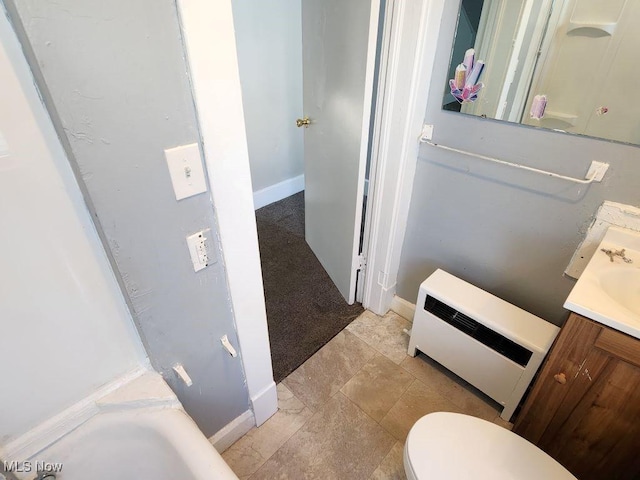 bathroom with heating unit, vanity, a bath, and toilet