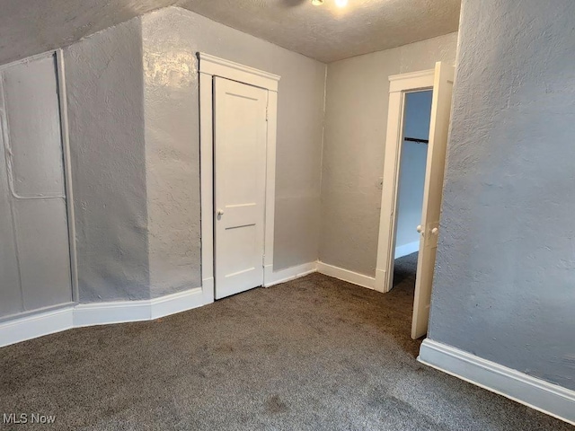 empty room with dark carpet, a textured ceiling, and vaulted ceiling