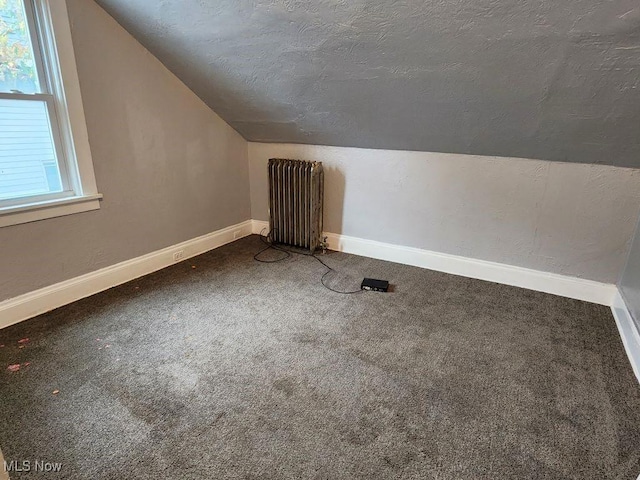 bonus room with a textured ceiling, radiator, carpet, and vaulted ceiling