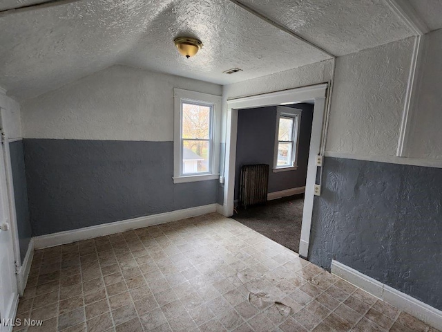 bonus room with lofted ceiling, a textured ceiling, and radiator