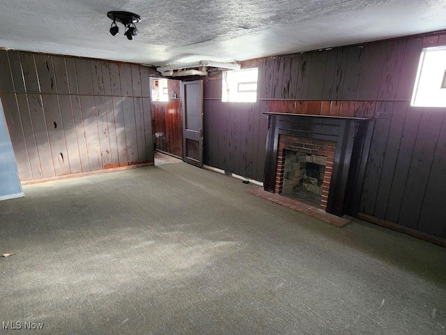 unfurnished living room with a textured ceiling, light carpet, wooden walls, and a brick fireplace