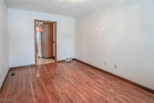 empty room featuring a textured ceiling and light wood-type flooring