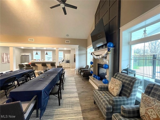 dining area featuring ceiling fan, hardwood / wood-style floors, high vaulted ceiling, and a textured ceiling