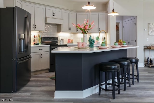 kitchen featuring backsplash, pendant lighting, stainless steel fridge with ice dispenser, dark hardwood / wood-style floors, and black electric range oven