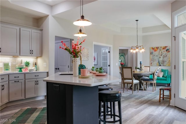 kitchen featuring backsplash, light hardwood / wood-style flooring, a kitchen island, and pendant lighting