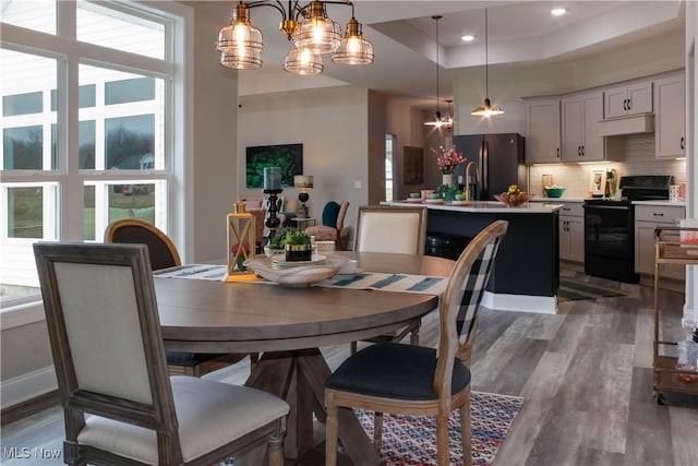 dining area featuring a tray ceiling, dark wood-type flooring, and an inviting chandelier