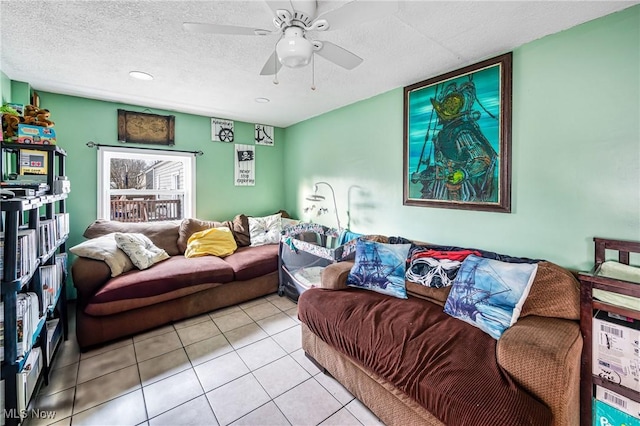 living room with ceiling fan, light tile patterned floors, and a textured ceiling