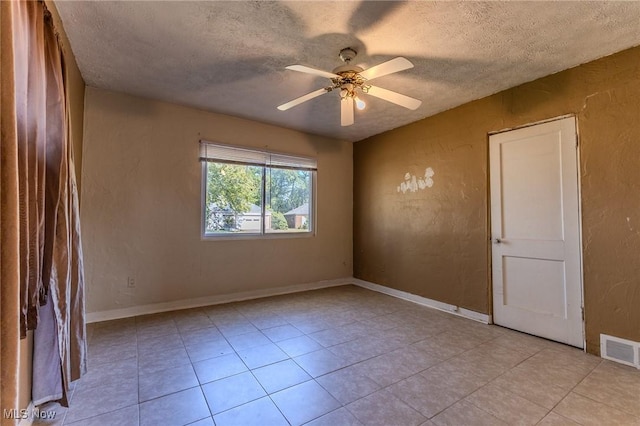 tiled spare room with a textured ceiling and ceiling fan