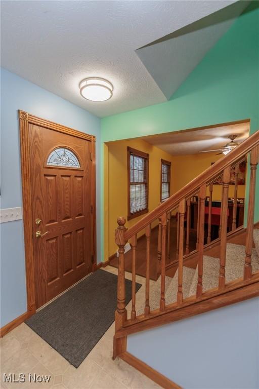 tiled foyer with ceiling fan and a textured ceiling