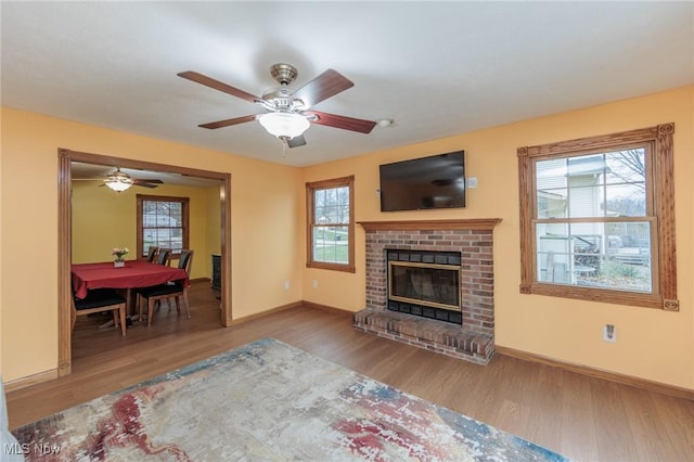 living room with hardwood / wood-style floors, a wealth of natural light, and a brick fireplace