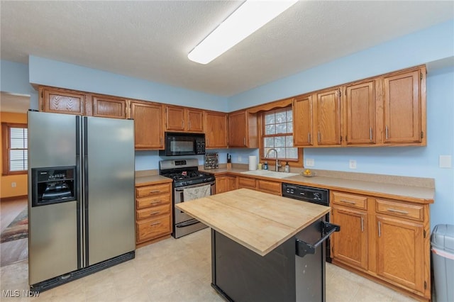 kitchen with a textured ceiling, sink, stainless steel appliances, and a wealth of natural light