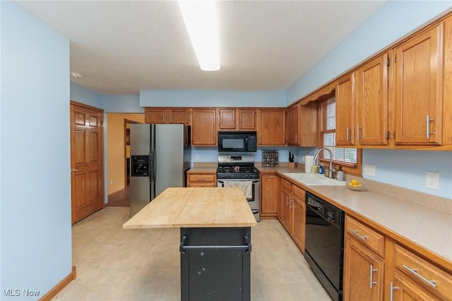 kitchen with sink, a center island, wooden counters, a textured ceiling, and black appliances