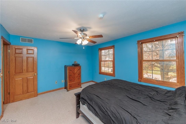 carpeted bedroom featuring ceiling fan and multiple windows