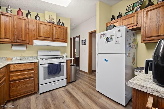 kitchen featuring light wood-type flooring, white appliances, and a textured ceiling