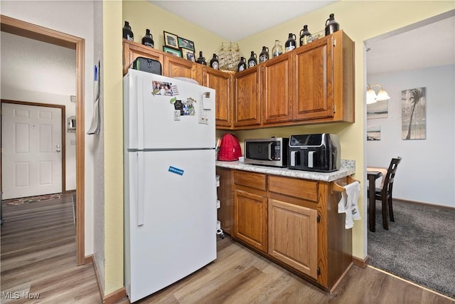 kitchen with white refrigerator, light hardwood / wood-style floors, and an inviting chandelier