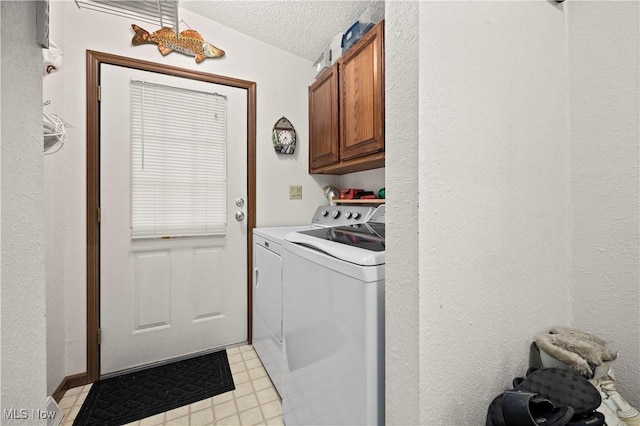 laundry area featuring cabinets, a textured ceiling, and washing machine and clothes dryer