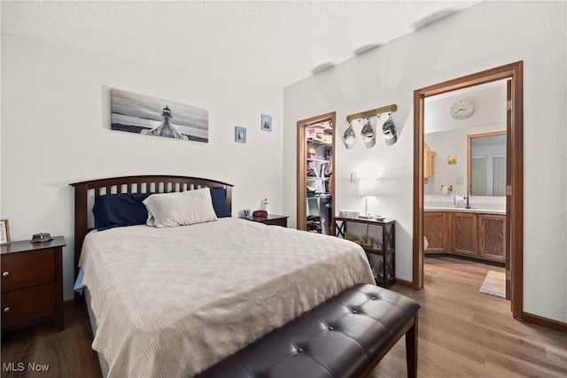 bedroom with sink, wood-type flooring, a textured ceiling, and ensuite bath