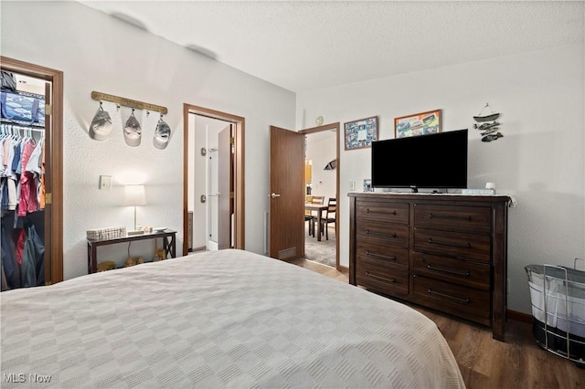 bedroom with a textured ceiling, a closet, and dark wood-type flooring