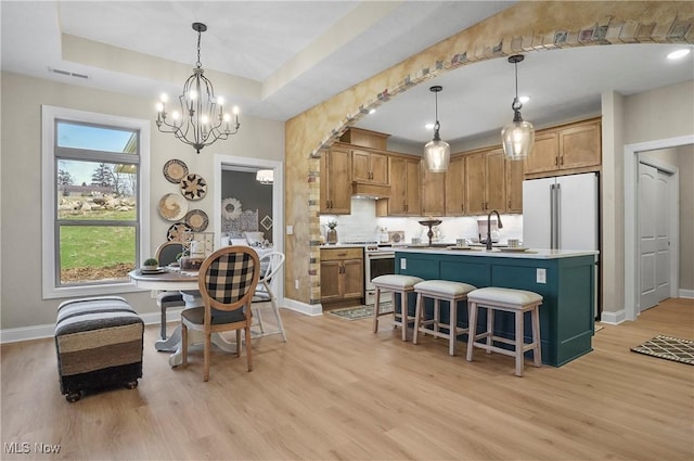 kitchen featuring pendant lighting, a center island with sink, light hardwood / wood-style flooring, high end fridge, and stainless steel range oven