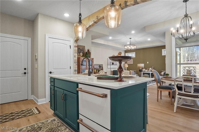 kitchen featuring sink, a notable chandelier, light hardwood / wood-style floors, decorative light fixtures, and a center island with sink