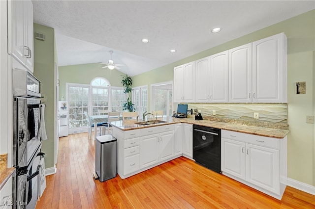 kitchen with kitchen peninsula, white cabinetry, dishwasher, and vaulted ceiling