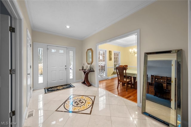 entryway with a wealth of natural light, light hardwood / wood-style floors, a notable chandelier, and ornamental molding