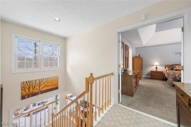 corridor featuring light colored carpet and a textured ceiling