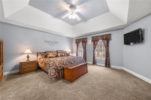 bedroom with carpet flooring, ceiling fan, and a tray ceiling