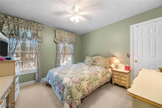 bedroom featuring light carpet, a textured ceiling, and ceiling fan