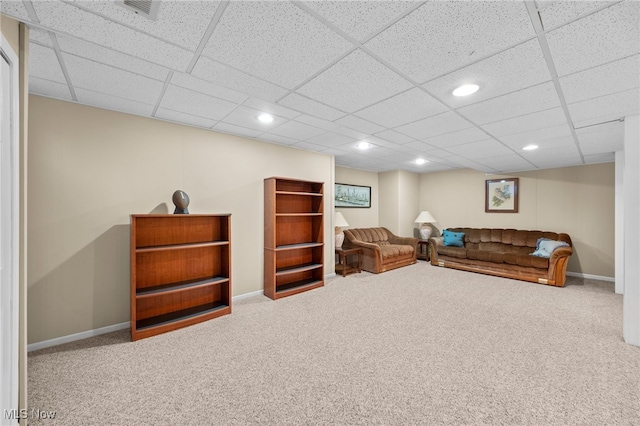 living room with a drop ceiling and carpet