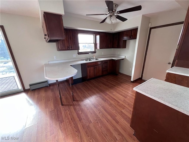 kitchen featuring a baseboard heating unit, dark brown cabinets, sink, and dark hardwood / wood-style flooring