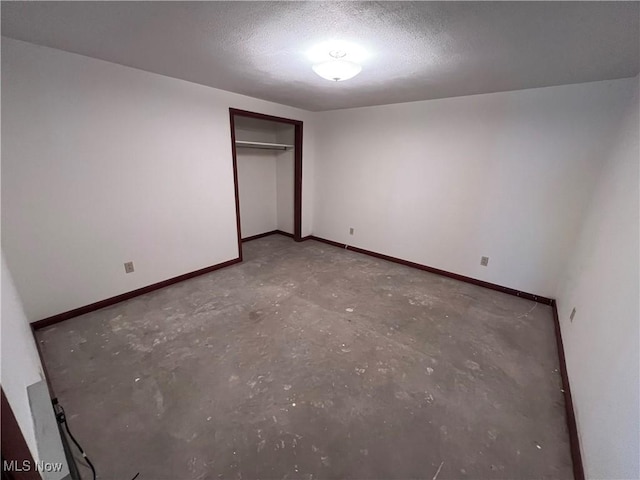 unfurnished bedroom featuring concrete flooring, a textured ceiling, and a closet