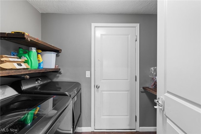 clothes washing area with washing machine and dryer and a textured ceiling