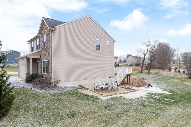 view of side of property with a garage, a patio area, and a lawn