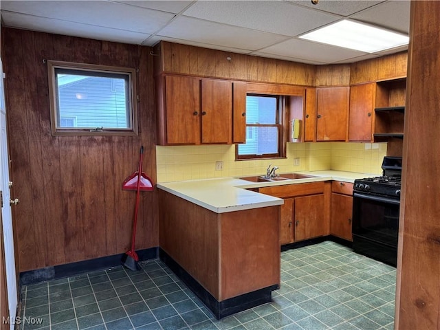 kitchen with backsplash, a drop ceiling, black gas range oven, and sink