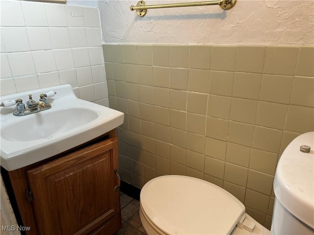 bathroom with tile patterned floors, vanity, tile walls, and toilet