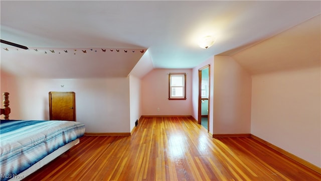 unfurnished bedroom with lofted ceiling and light wood-type flooring