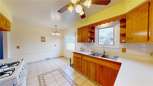 kitchen featuring backsplash, ceiling fan with notable chandelier, sink, hanging light fixtures, and white range oven