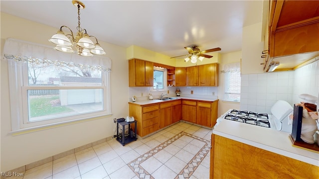 kitchen with pendant lighting, ceiling fan with notable chandelier, light tile patterned floors, and sink