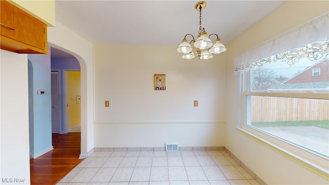 spare room with a chandelier and light wood-type flooring