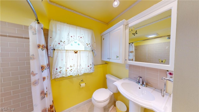 bathroom featuring a shower with shower curtain, backsplash, ornamental molding, sink, and toilet