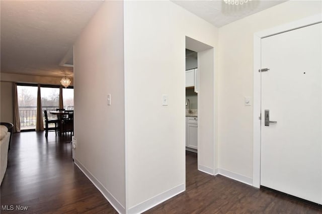 corridor with a notable chandelier, dark hardwood / wood-style floors, and sink