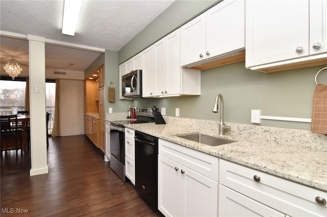 kitchen with appliances with stainless steel finishes, light stone counters, sink, dark hardwood / wood-style floors, and white cabinetry