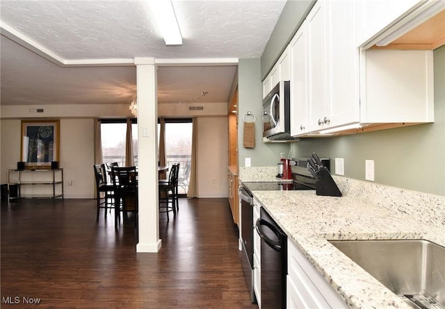 kitchen with light stone countertops, white cabinetry, dark wood-type flooring, stainless steel appliances, and a textured ceiling