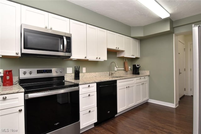 kitchen with appliances with stainless steel finishes, white cabinetry, dark wood-type flooring, and sink