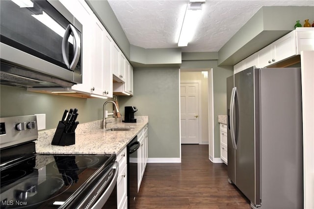 kitchen featuring light stone countertops, sink, dark wood-type flooring, white cabinets, and appliances with stainless steel finishes