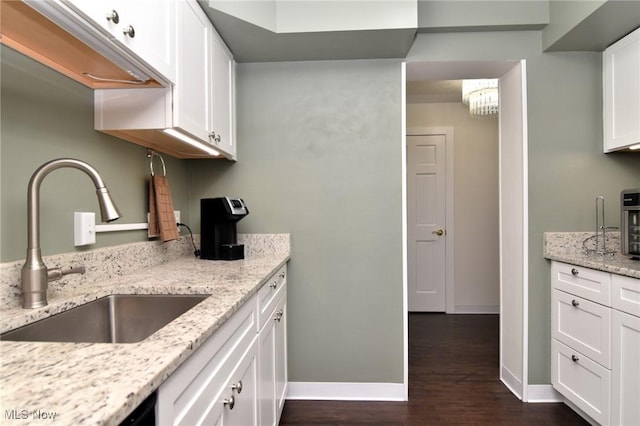 kitchen featuring light stone counters, dark hardwood / wood-style flooring, white cabinetry, and sink