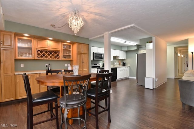 dining room with a textured ceiling, sink, dark hardwood / wood-style floors, and a notable chandelier