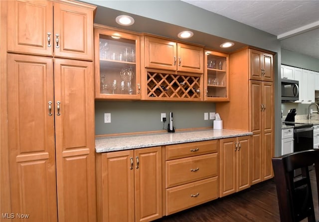 bar featuring light stone countertops, dark hardwood / wood-style flooring, and appliances with stainless steel finishes